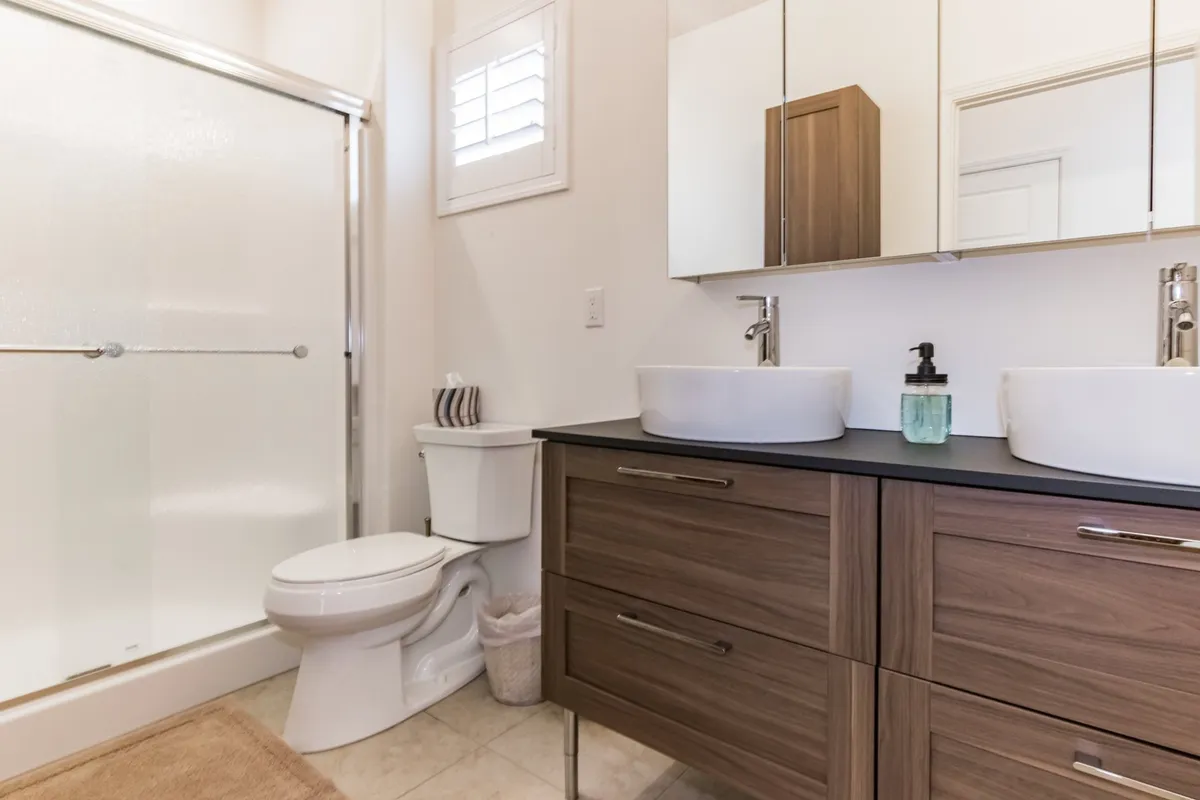 A modern bathroom featuring dual sinks with contemporary cabinetry and a sleek glass shower enclosure. The space is clean, well-lit, and offers a spa-like experience for guests to unwind and refresh.