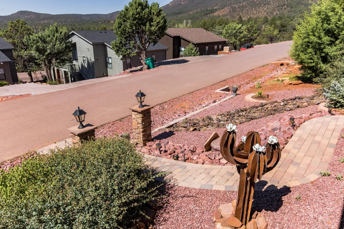 The scene captures a welcoming outdoor pathway lined with a cactus sculpture, modern street lamps, and lush landscaping. The inviting pathway hints at leisurely strolls and vibrant community life, perfect for family exploration and discovering local shops or eateries in downtown Pine.