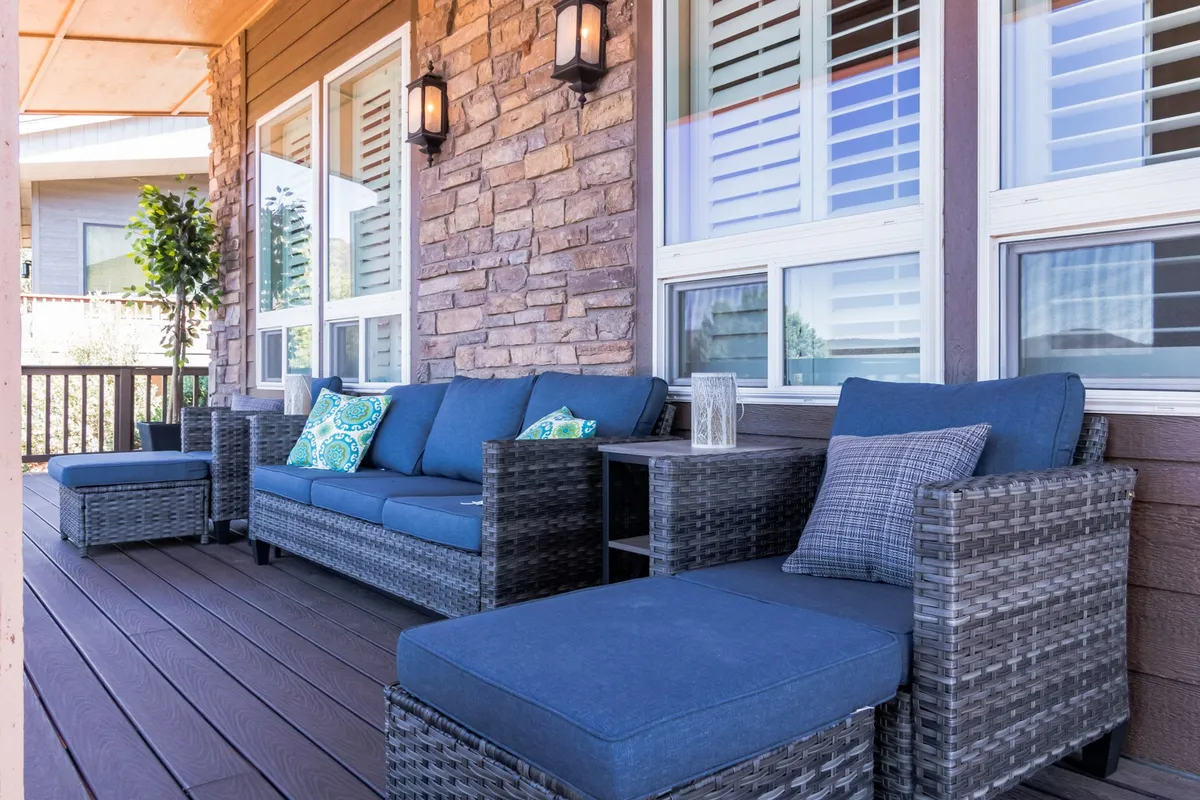 A cozy exterior seating area features comfortable cushioned chairs, a textured stone wall, and a small side table, all set beneath warm porch lights. The space invites relaxation after a day of adventure, perfect for unwinding with the family (and pets) in the evenings.